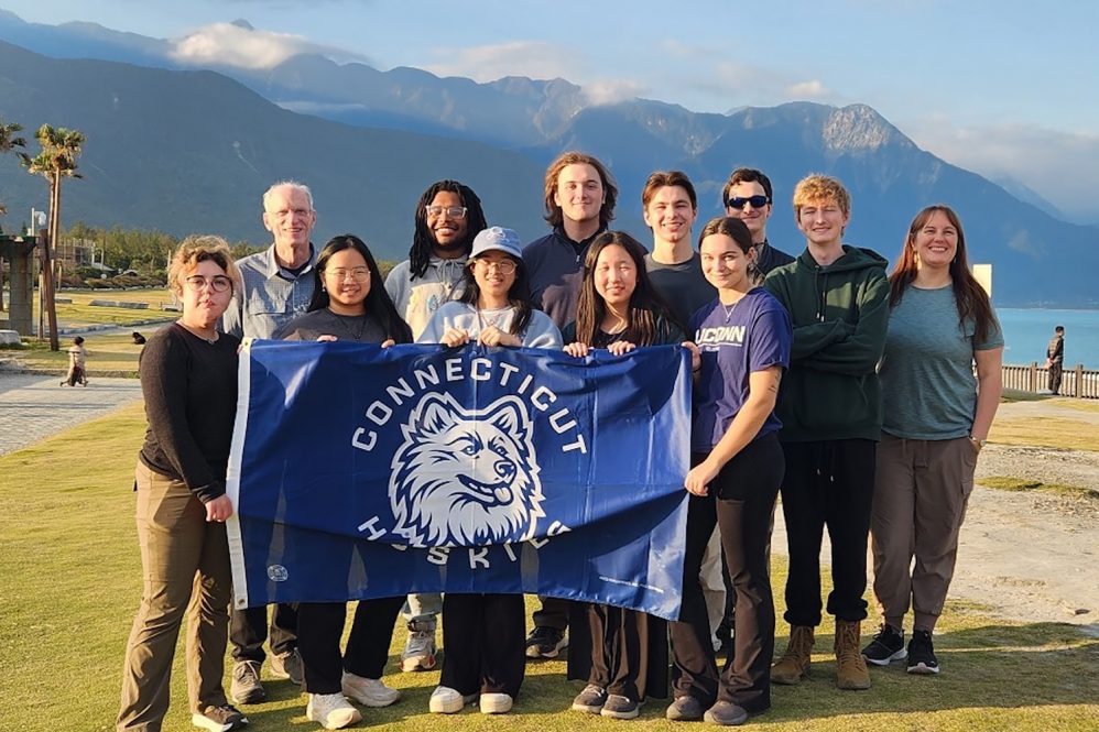 UConn Students holding a UConn Connecticut Huskies flag