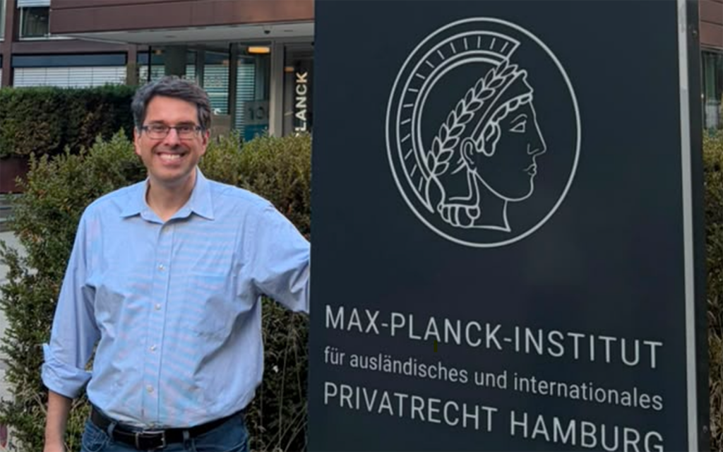 Professor Bird standing next to a sign of the Max Planck Institute for Comparative and International Private Law in Hamburg, Germany.